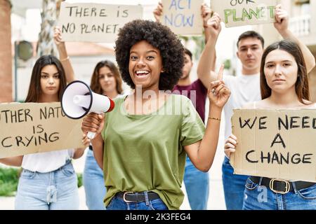 Group of young friends protesting and giving slogans at the street smiling happy pointing with hand and finger to the side Stock Photo