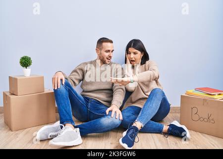 Young couple moving to a new home looking at the watch time worried, afraid of getting late Stock Photo