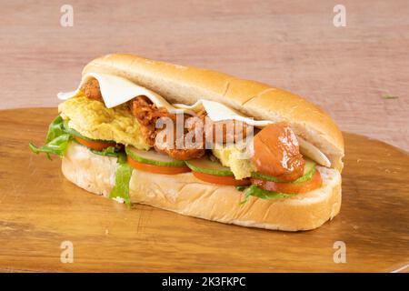 fresh submarine sandwiches with ham, cheese, bacon, tomatoes, lettuce, cucumbers and onions on dark wooden background Stock Photo