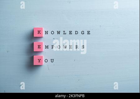 Knowledge empowers you sign written on pink wooden blocks and blue wooden backgorund. Stock Photo