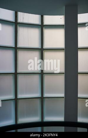 Interior of building looking at opaque of curved window constructed from glass blocks during daytime Stock Photo