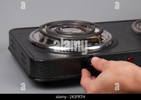 hand turns on the electric stove, temperature control. Stock Photo