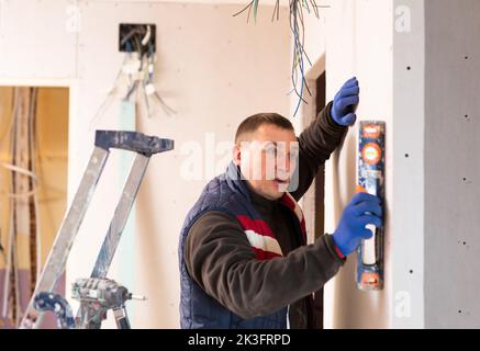 Builder checks the vertical of the wall using level Stock Photo