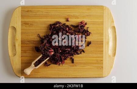 Tea made from dried pomegranate flowers. Increases immunity. Wooden spatula with tea and a handful of tea mixture on a wooden board. Stock Photo