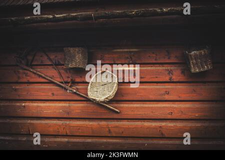 Old peasant tools hanging on wooden wall on animal farm. Stock Photo