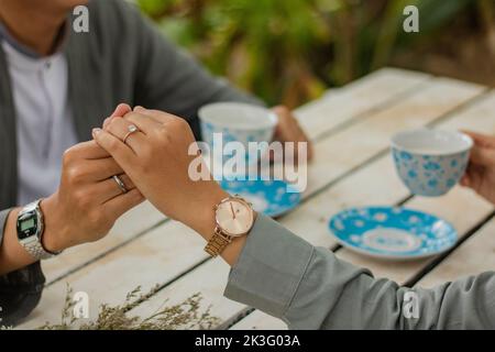 close up of a happy young couple holding hands with each other and enjoying a cup of drink in the cafe Stock Photo