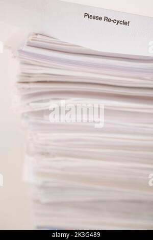 Please Re-cycle notice on top of pile of white paper sheet office documents. Stock Photo