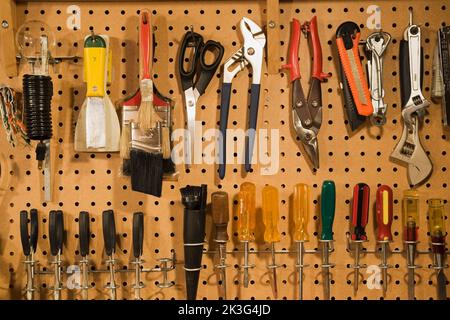 Assorted manual tools on pegboard in workshop. Stock Photo