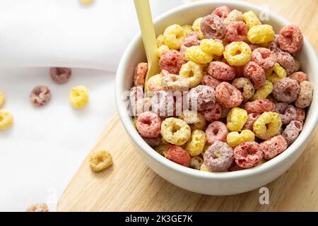 Healthy food concept, Colorful ring cereals in bowl on saucer wooden and falling on white cloth. Stock Photo
