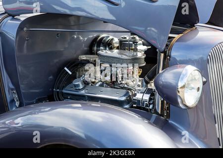 An open hood exposes the modified engine of a classic car. Stock Photo