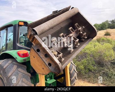 Forestry land clearing mulcher attached to wheeled tractor. Stock Photo