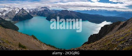 Panoramic view of Mt. Garibaldi towering over Garibaldi Lake's beautiful glacial blue water from Panorama Ridge. Stock Photo