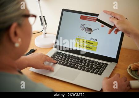 Grandson paying for sunglasses his grandmother had choosen in online shop Stock Photo