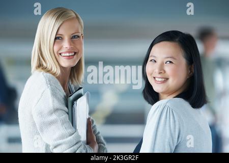 Heading to class. Two young students smiling while looking at the camera. Stock Photo