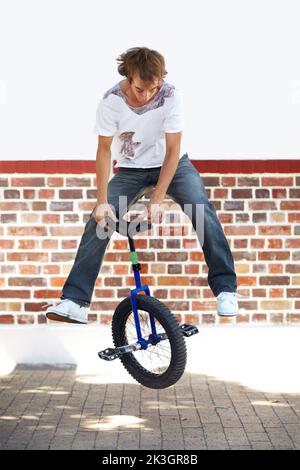Turning seats. Full-length shot of a young man riding a unicycle. Stock Photo