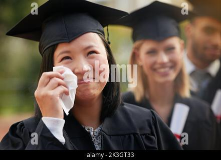 Take pride in how far you have come. An ecstatic young graduate shedding tears of joy at her graduation. Stock Photo