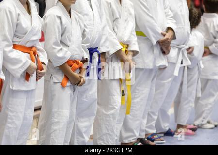 Shallow depth of field (selective focus) details with both children and adults martial arts students in their specific outfits (kimonos). Stock Photo