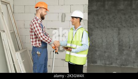 Contractor and engineer shaking hands to agree to build a house or building. construction worker accepts job wage terms. Client shaking hands with Stock Photo