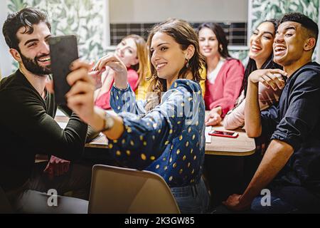Group of cheerful friends gathering at home and taking joyful selfie memories with their smartphone - millennials youth generation people having fun - Stock Photo