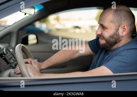 Middle-aged man driving his car, pressing horn while in a traffic jam. Car Driver Honking Stock Photo