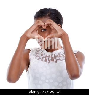 I believe in a thing called love. A young woman making a heart gesture against a white background. Stock Photo