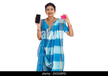 Portrait of a Bengali woman holding credit card and mobile phone against white background Stock Photo