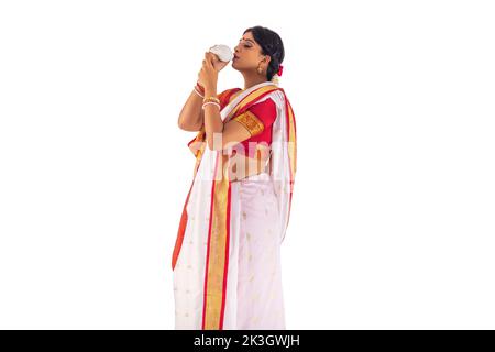 Bengali woman in white sari playing sankh Stock Photo