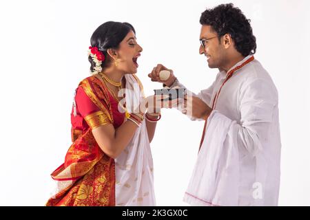 Portrait of Bengali man feeding rosogolla to his wife Stock Photo