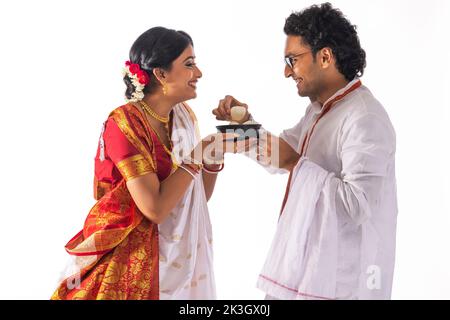 Portrait of Bengali man feeding rosogolla to his wife Stock Photo