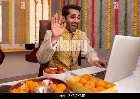 Man having video call on laptop in office during Diwali celebration Stock Photo