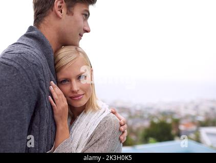 Safe in his arms. A husband embracing his wife while he looks over the city view. Stock Photo