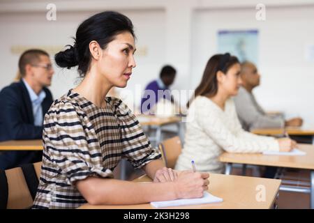 Interested adult korean woman on lesson in school auditorium Stock Photo