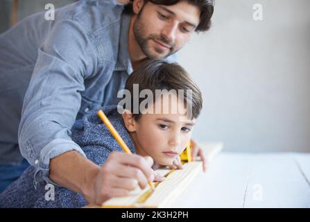 Helping dad with his carpentry. A father and son doing woodwork together. Stock Photo