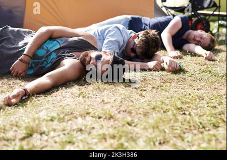 Theyve had one too many...three young men lying on the grass at an outdoor festival. Stock Photo