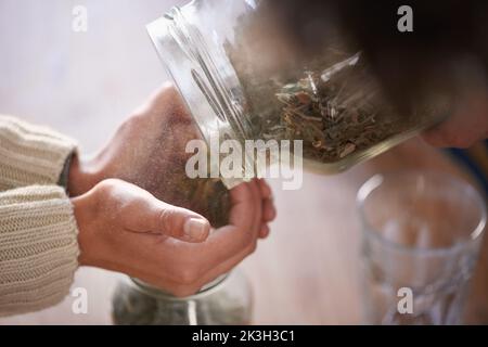 Putting tea leaves in jars. a young womans hands putting tea leaves in a jar. Stock Photo