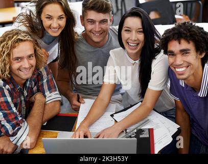 Having a blast studying. Portrait of a group of positive-looking university students using a alptop. Stock Photo