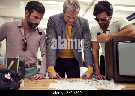 Well, here are our choices...Three designers clad in retro 70s wear working on a project together. Stock Photo