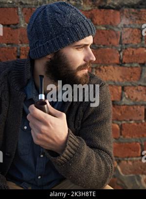 Smoking a pipe. a bearded man smoking a pipe outside. Stock Photo