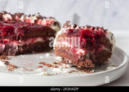 Black forest gateaux dessert, part eaten, on a grey stoneware plate Stock Photo