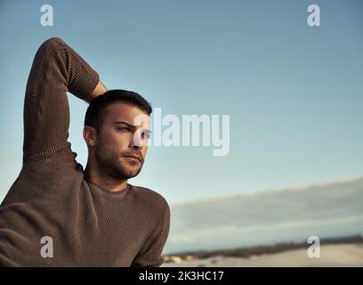 Contemplation by the seaside. A handsome young man looking thoughtful on the beach. Stock Photo