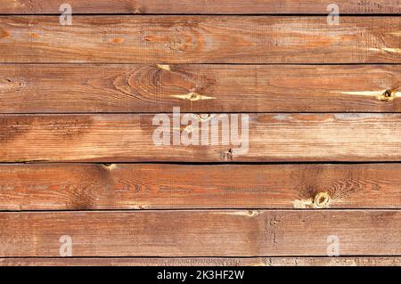 Vintage brown wood texture background with knots, nicks and scratches. Vintage wooden dark horizontal boards in the sun. Stock Photo