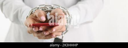 Woman hands tied with chain hold smartphone Stock Photo