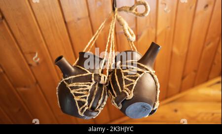 Two earthenware jars with spouts are suspended on a rope. Close-up Stock Photo