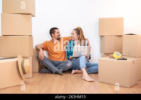 Household Move. Attractive couple with moving boxes becoming independent and opening a new home. Furnish an empty house. Stock Photo