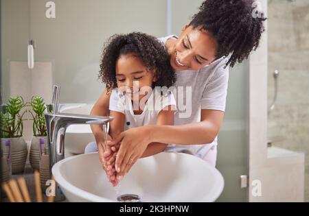 Family, washing hands and child with mom rinsing, cleaning and good hygiene against bacteria or germs for infection or virus protection in bathroom Stock Photo