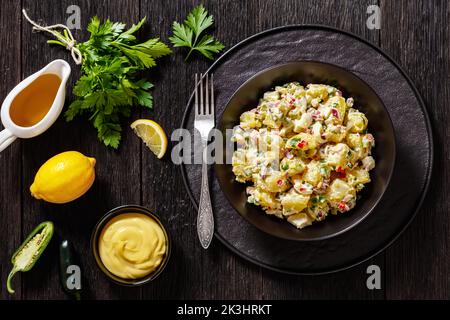 shout hallelujah potato salad with pickles, celery, eggs, jalapeno and mayonnaise dressing in black bowl, southern american cuisine, flat lay Stock Photo