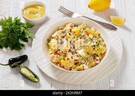 hallelujah potato salad with pickles, celery, eggs, jalapeno and mayonnaise dressing in white bowl on wooden table, american cuisine, horizontal view Stock Photo