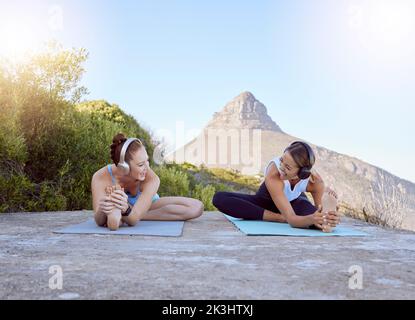 Yoga, friends and nature with a sports woman and female athlete training outdoor for exercise, workout and fitness. Health, music and zen with two Stock Photo