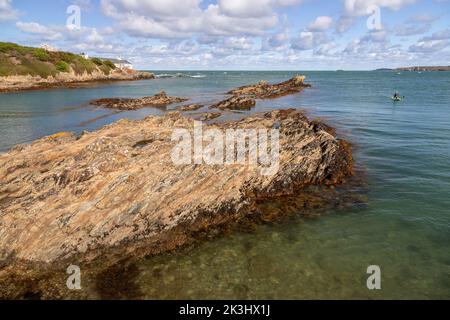Rocks and paddleboarder at Bull Bay, Anglsey, North Wales Stock Photo