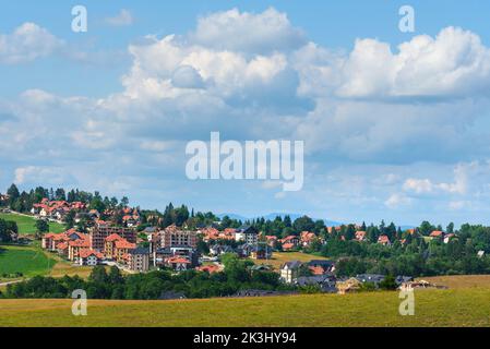Beautiful picturesque Zlatibor region landscape with distinctive architectural style houses scattered over green hills on sunny summer day Stock Photo